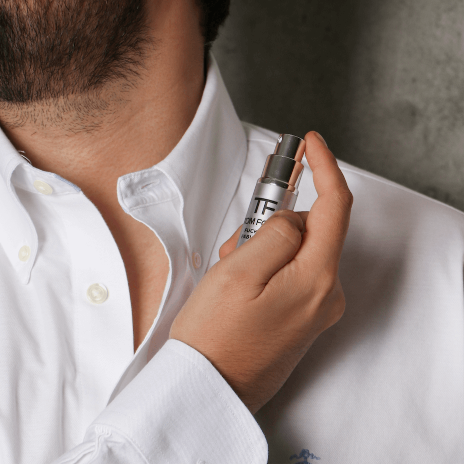Hombre aplicando perfume en el cuello, usando camisa blanca. Decant.